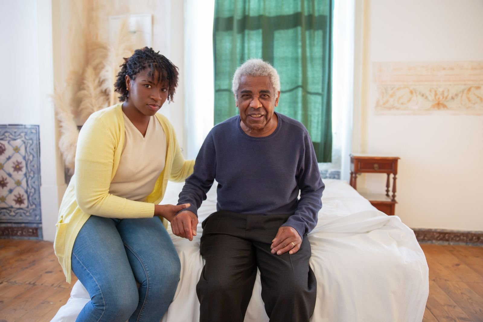 A caregiver holding hands with a smiling older man at home