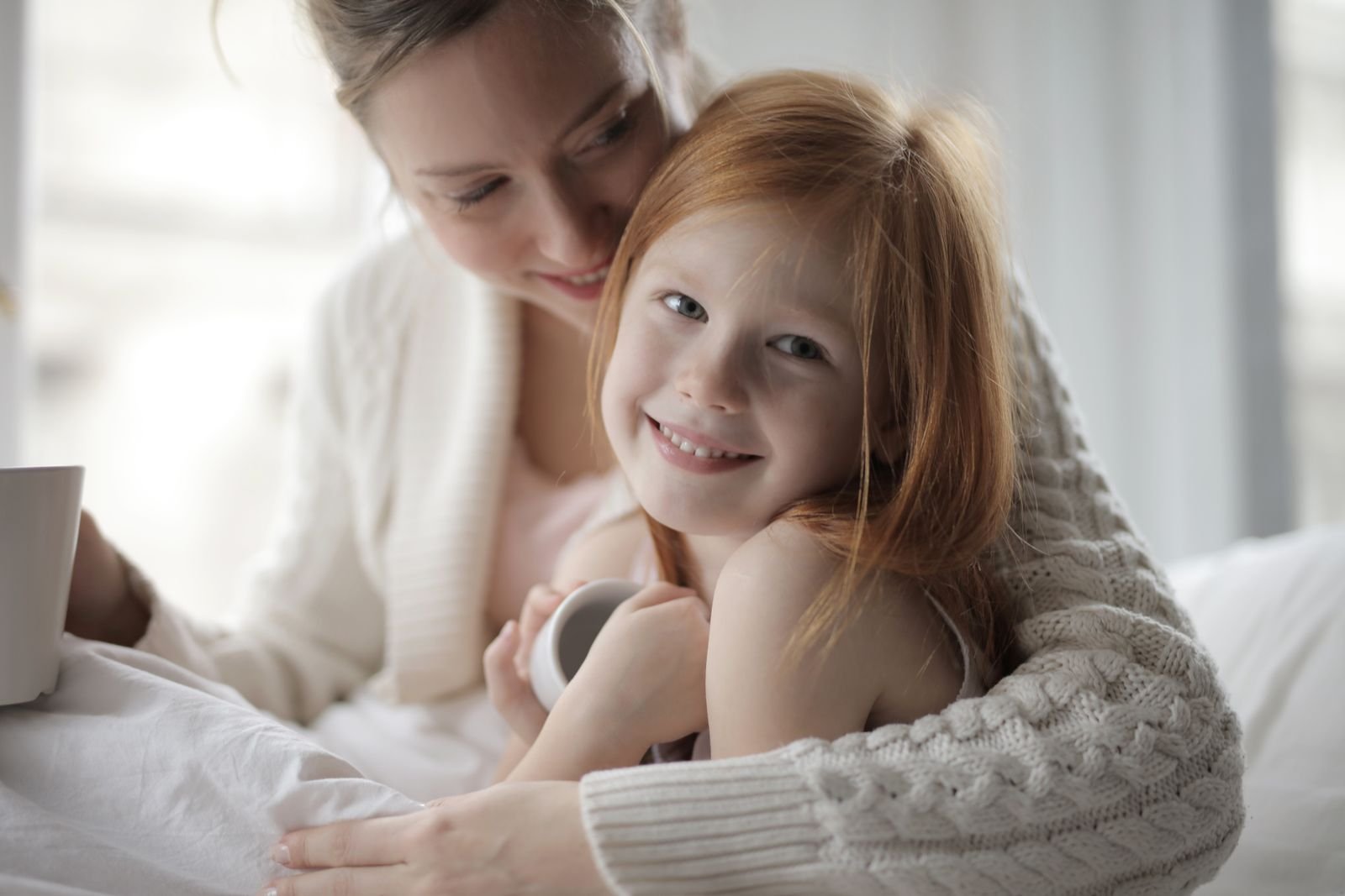 A mother embracing her smiling daughter at home